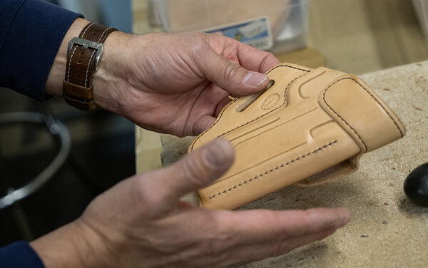 Harvey holds up an assembled holster that must still go through a finishing process before being sent to the customer it is being fashioned for. (PHOTO: MARC LUTZ, IBR)