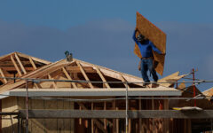 A construction worker carries a sheet of OSB sheathing as he builds a roof on a residential homes in Irvine, California, on March 28, 2025. (PHOTO: REUTERS/Mike Blake/File Photo)