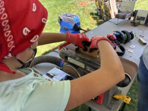 One of the camp's attendees uses a belt sander to smooth out the edges on a piece of wood for use in one of five projects. (PHOTO: LET'S BUILD IDAHO)